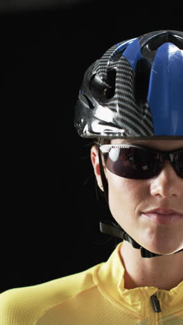 vertical video: caucasian female athlete wearing cycling helmet, black background
