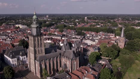 rotating aerial around walburgiskerk cathedral with golden weathercock in medieval hanseatic town zutphen in the netherlands showing drogenapstoren and watertower in the back in flat dutch landscape