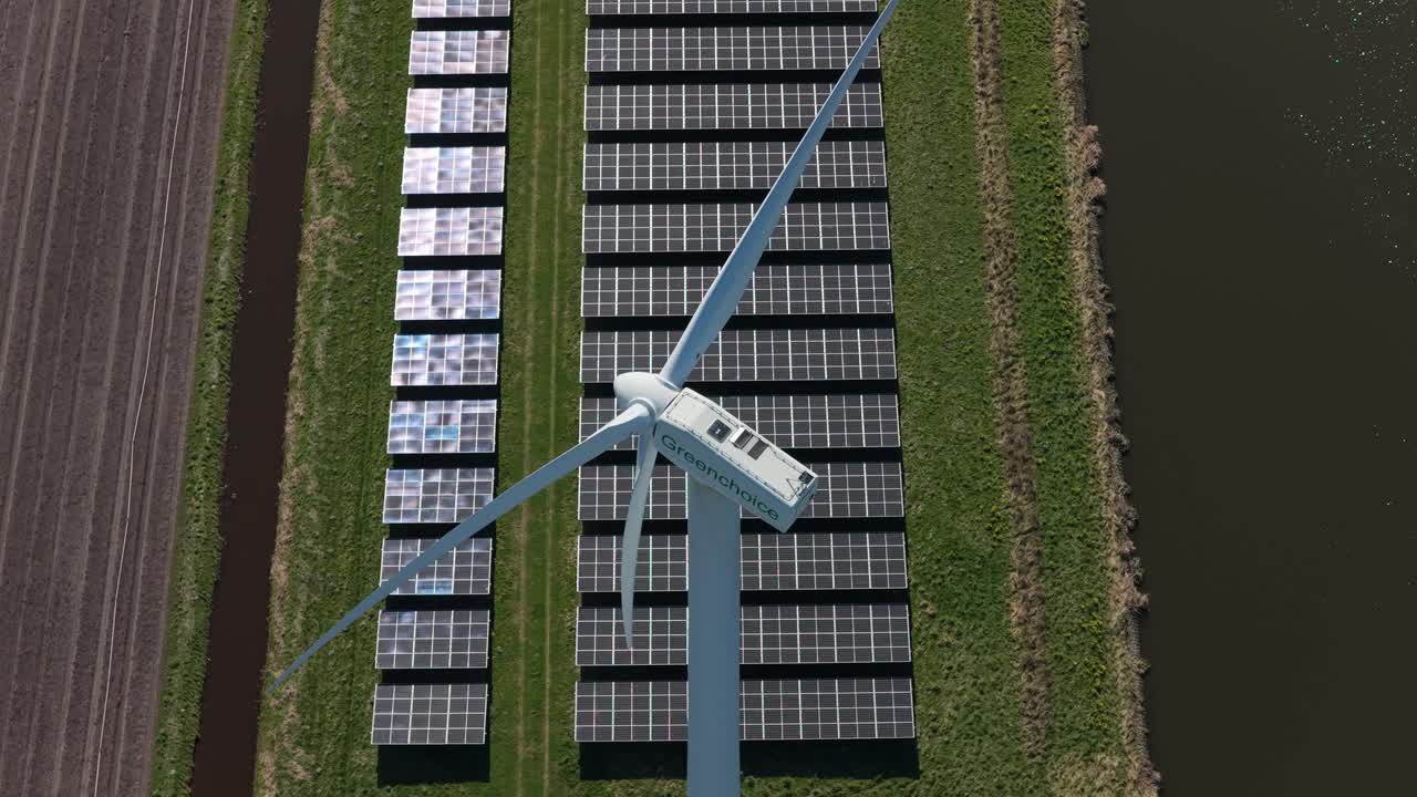 Vista aerea di una turbina eolica e pannelli solari che generano energia rinnovabile.