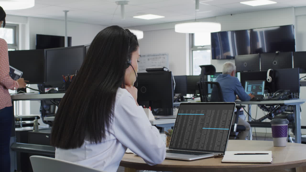 mujer asiática sentada en el escritorio viendo el procesamiento de datos de codificación en la pantalla del portátil