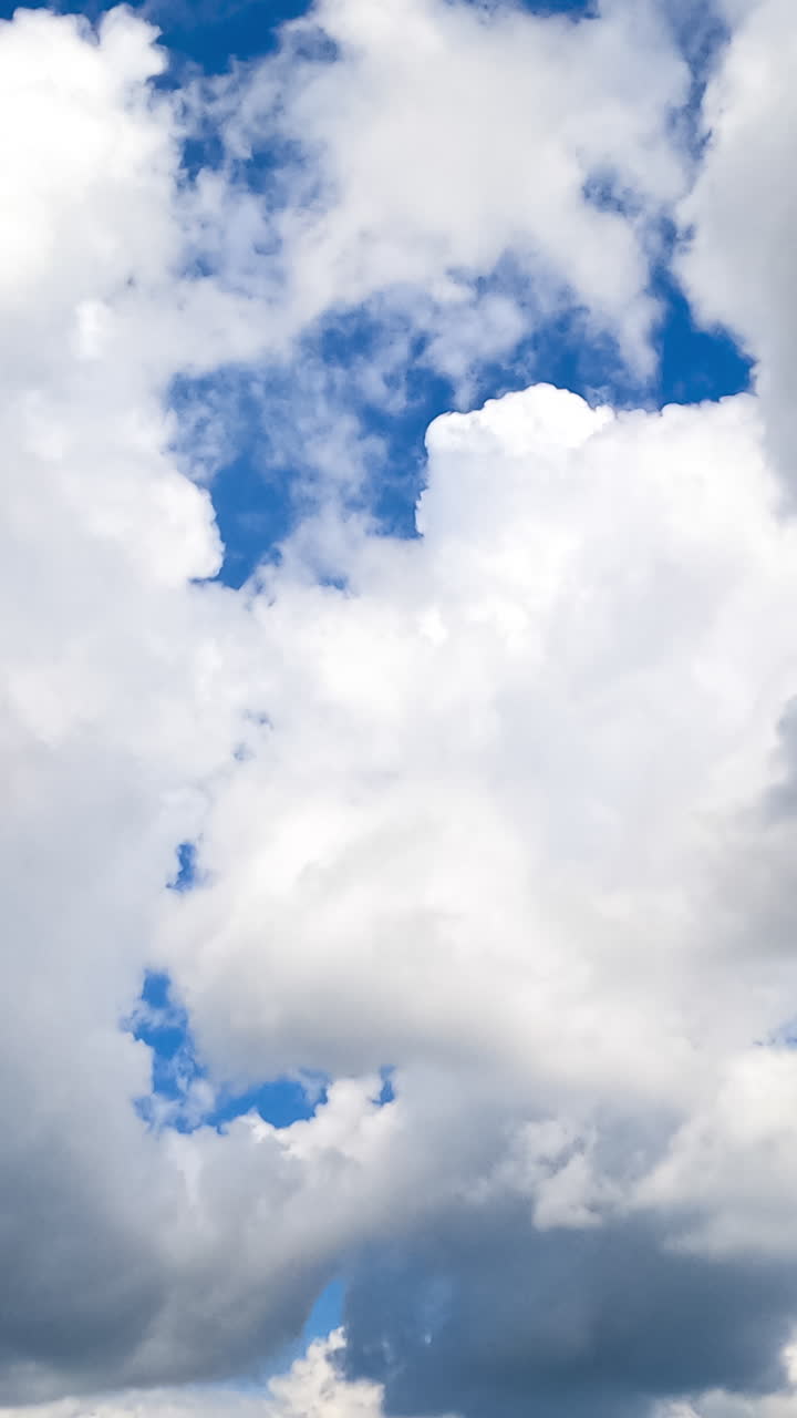 Moving forward among the amazing cumulus clouds. White clouds in the bright sunlight on summer day. Timelapse. Vertical video