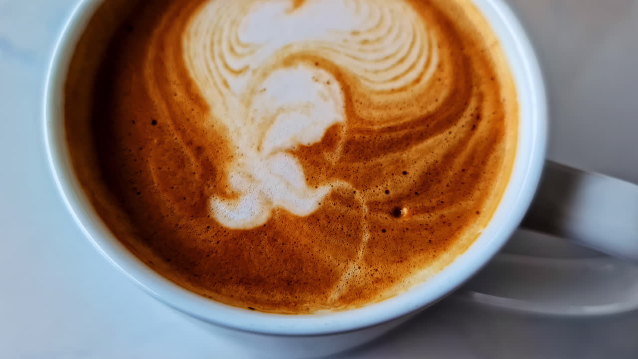 Latte with heart shape art on white table, warm and cozy feel