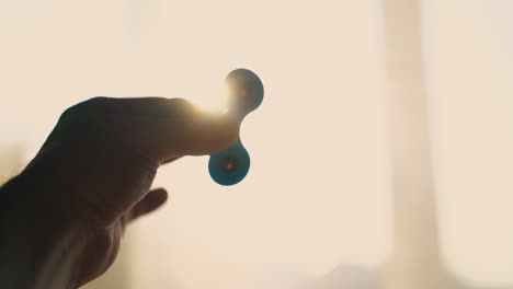 man hand holds turning spinner against bright back light