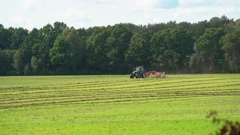 A-modern-tractor-with-mower-mows-green-grass-during-summer-for-livestock-feeding-or-hay-in-Lithuania,-Europe