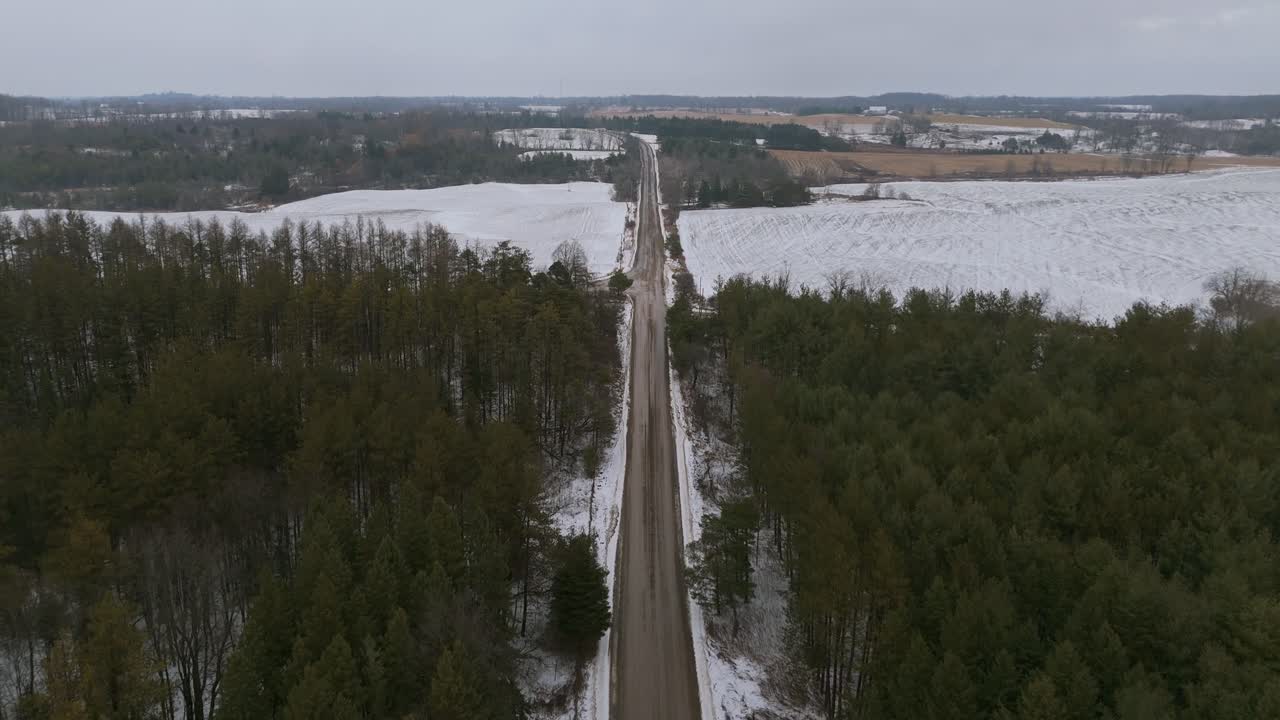 A road stretches through snow-covered fields and a forest in Alton Grange, Ontario
