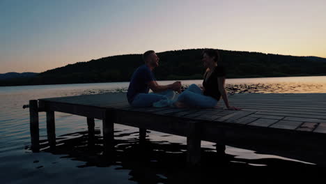 couple enjoying a romantic sunset on a lake pier