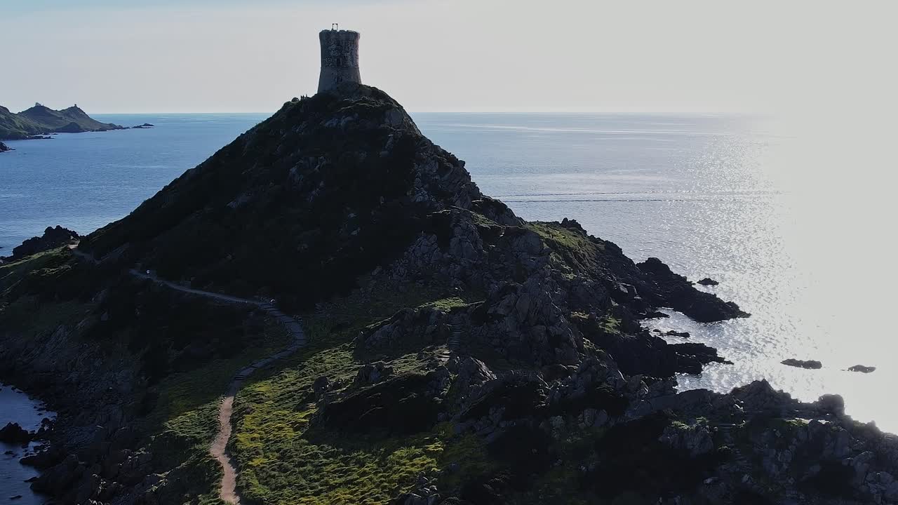 Smuk kystlinje på Korsika med et tårn på en bakketop ved havet