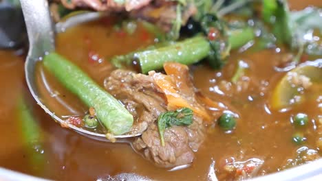 close up footage of hot and spicy beef clear soup curry with long curd beans and holy basil leaves, one of the delicious homemade dish in thailand