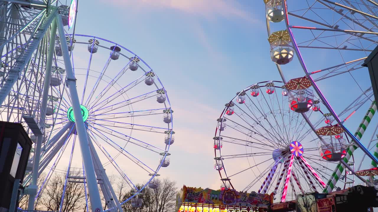 четыре аттракциона колеса обозрения вращаются на улице на рассвете, широкий снимок, ярмарочный аттракцион