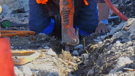 Hombre-Limpiando-Escombros-A-Mano-En-La-Trinchera-Con-Su-Martillo-Neumático-Cerca-De-La-Cámara-Alejándose