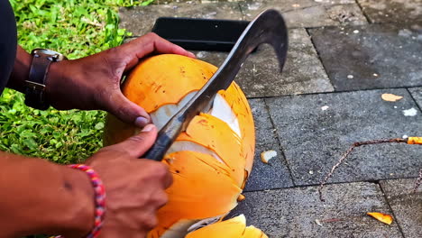 man slices coconut in kuta selatan, bali outdoors with a knife
