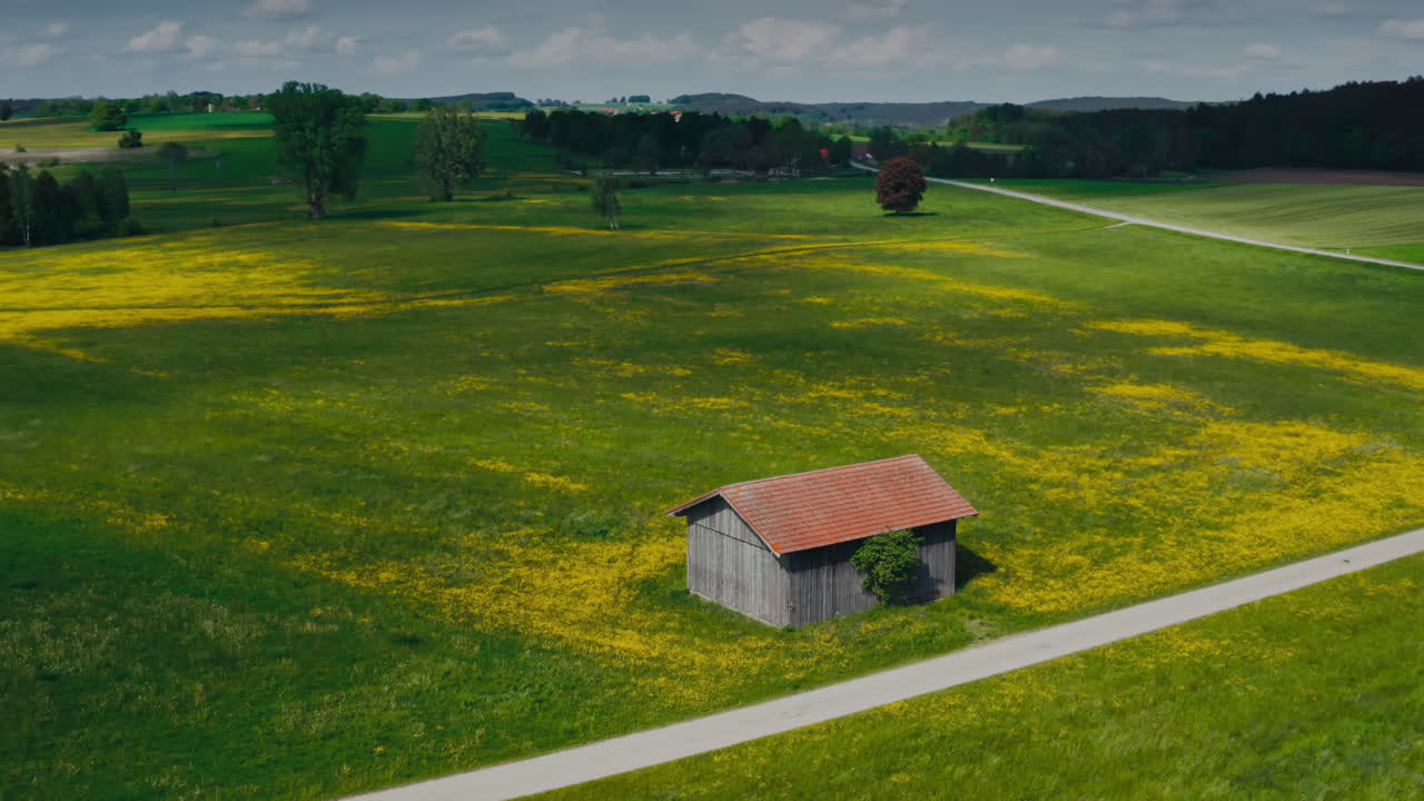 Drone shot of a farm equipment shed beside a cross-country road, surrounded by fields on a sunny day