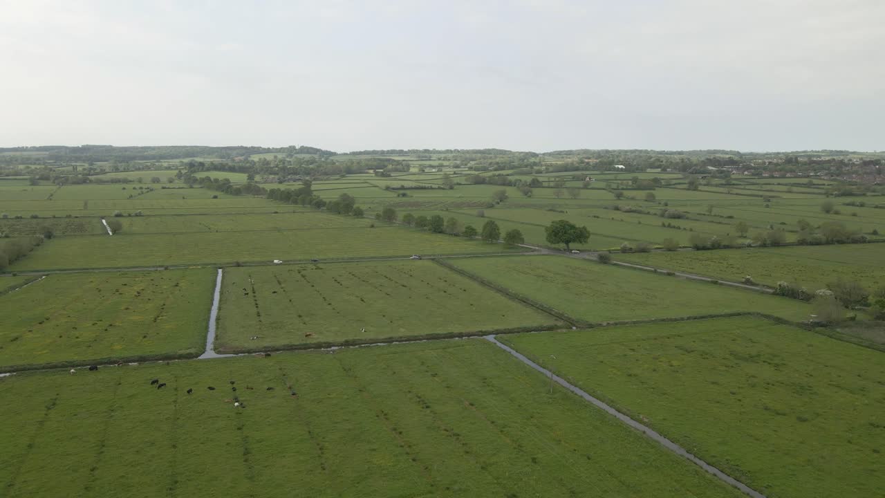 Aerial view of Glastonbury, drone moving to the left showing the houses and the Main Street leading to the Tor. green fields and water course around the houses . 4K,