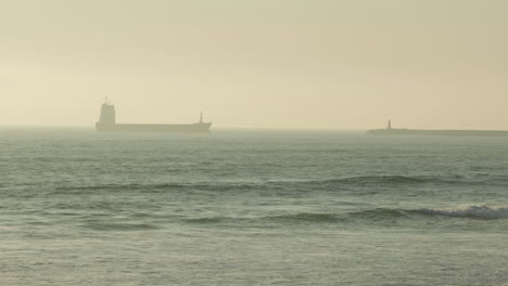 freight barge sailing across the sea obscure by morning fog in figueira da foz, portugal