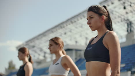 female runners at athletics track crouching at the starting blocks before a race. in slow motion.