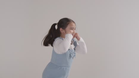 studio portrait of hyperactive girl smiling and giving thumb up gesture against white background