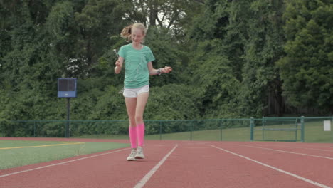 cute young girl teenager walks on track twirling her headphones in slow motion