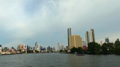 Toma-Pov-Desde-Un-Barco-Durante-Un-Recorrido-En-Barco-Por-El-Río-Chao-Phraya-En-La-Ciudad-De-Bangkok-Durante-Un-Día-Nublado,-Tailandia