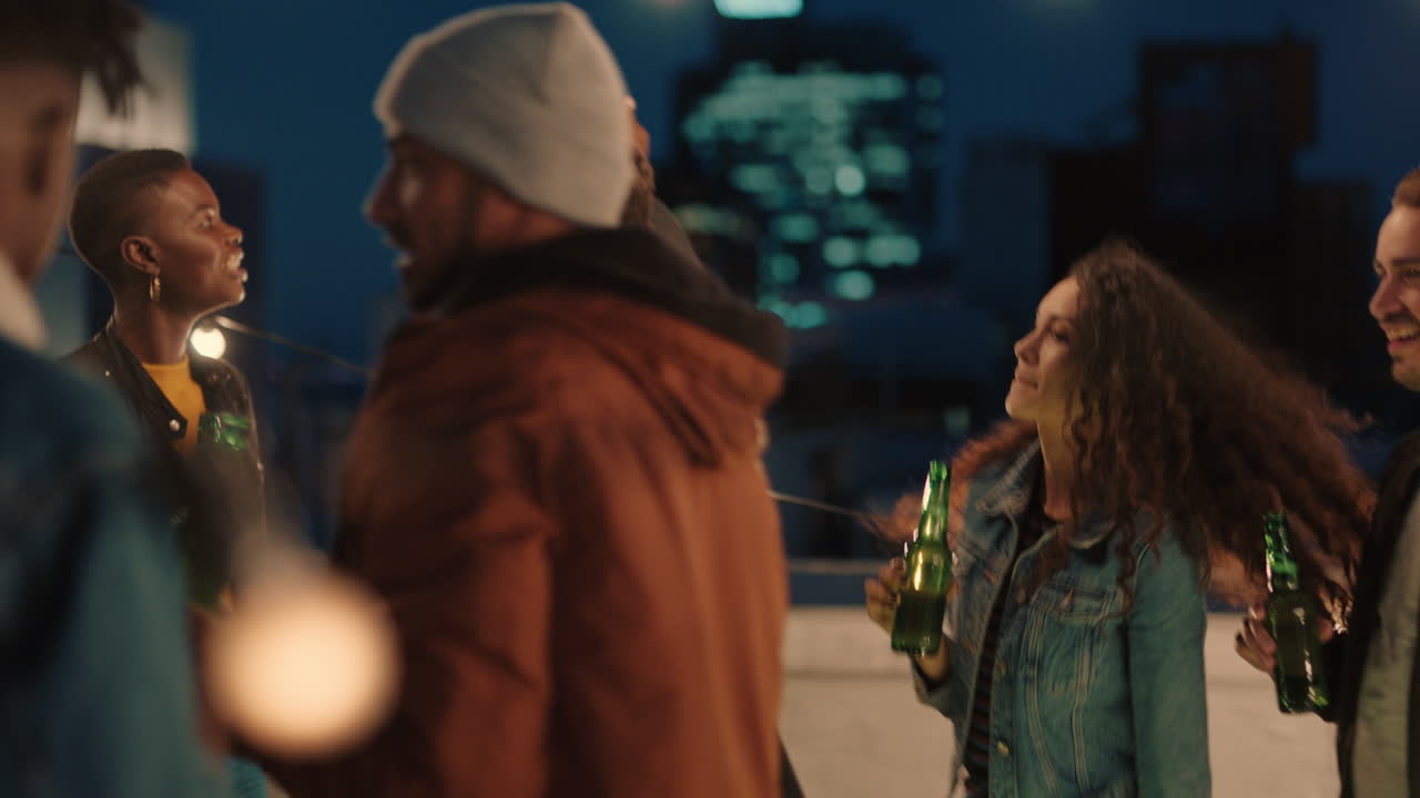 행복한 옥상 파티 친구들이 즐겁게 젊은 아프리카계 미국인 남자가 스마트폰을 사용하여 사진을 찍고 밤에 소셜 미디어에서 주말 라이프 스타일을 공유합니다.