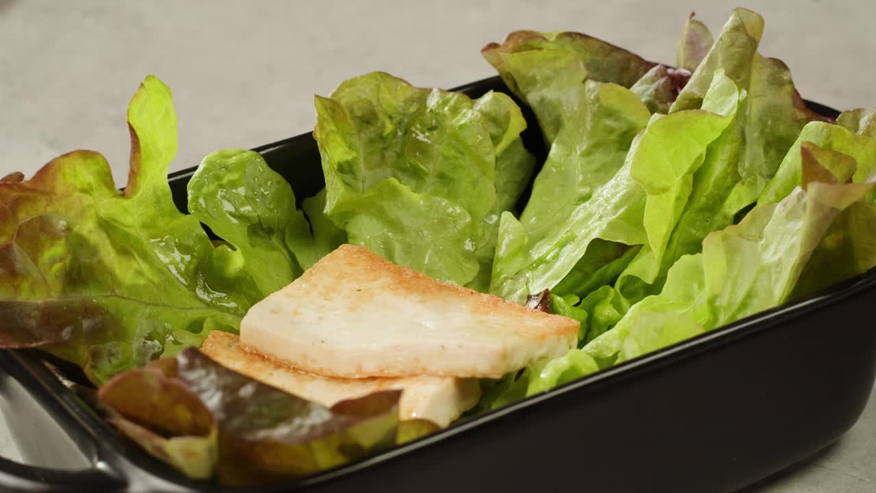 Fried tofu with sesame seeds and spices on cast iron pan, cooking japanese salad. Healthy ingredient for cooking vegan vegetarian diet food. Roasted tofu over black background.