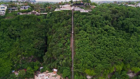 a small cliff railway makes its way down a lush coastal slope toward a beach club by the ocean offering a unique and picturesque journey from the highlands to the shore.