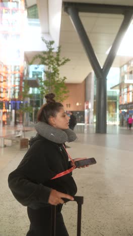 woman at airport with luggage and neck pillow