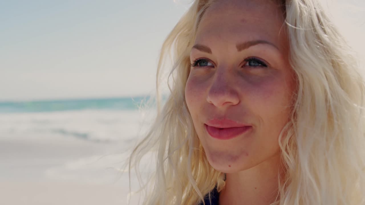 Kvinde står på stranden i solskinnet 4k