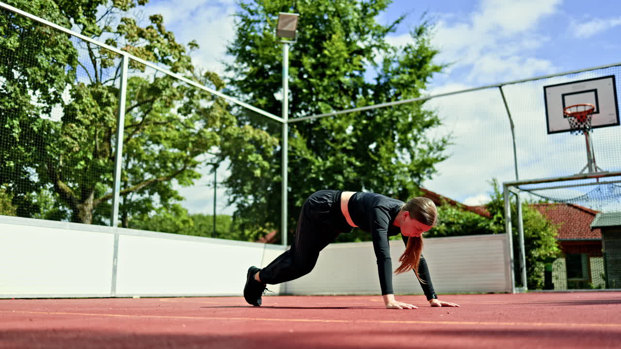 Sporty woman doing exercises on a sports ground outdoors. Woman doing sports in the park on a sports ground. Healthy lifestyle