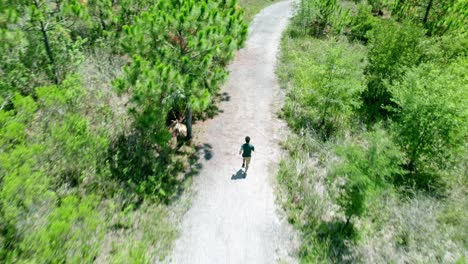 Video-Aéreo-De-Un-Hombre-Caucásico-Corriendo-En-Un-Parque-Público-Verde-Y-Soleado