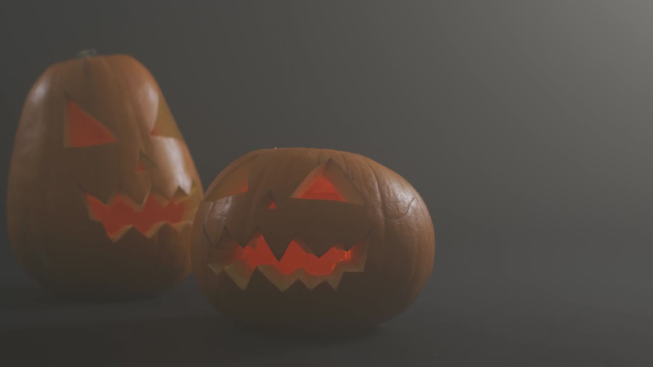 efecto de humo sobre dos cara aterradora tallada calabaza de halloween contra un fondo gris