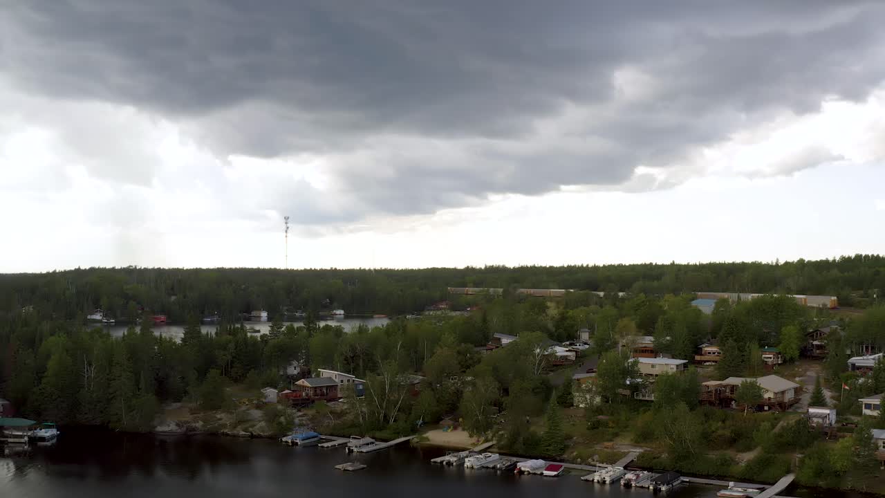 Storm clouds approaching a collection of cottages in the Canadian whiteshell. Aerial pan upwards