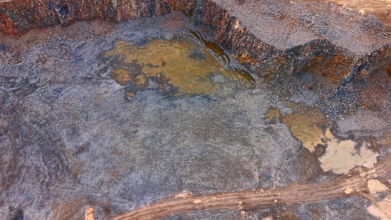 Cantiere edile con veicoli. Macchinari pesanti lavorano sul terreno in un cantiere con grandi rocce e terreno aperto sullo sfondo.