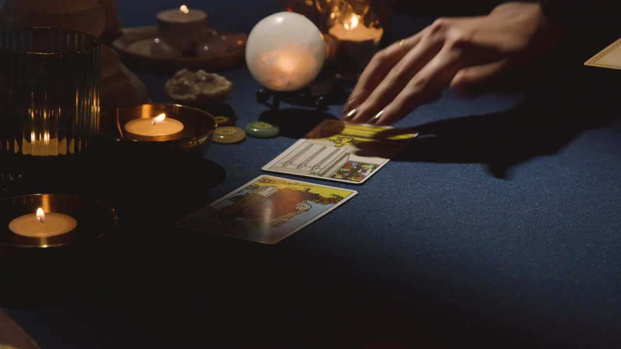 primer plano de una mujer colocando cartas para la lectura del tarot en la mesa 3 a la luz de las velas