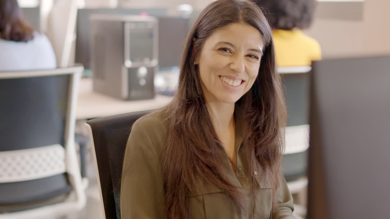Woman working with computer and then smiling in a coworking