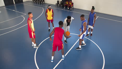 multiracial male basketball players with black male coach beginning game in gym