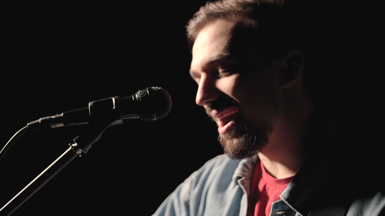 un músico está tocando la guitarra en un gran escenario con miembros de la audiencia sosteniendo linternas en el fondo. el auditorio está lleno de hermosas luces parpadeantes.
