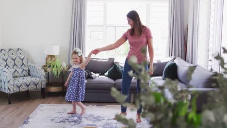 Caucasian-mother-and-daughter-having-fun-dancing-in-living-room