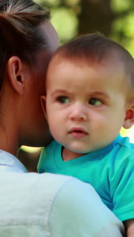 madre sosteniendo a su hijo en el parque