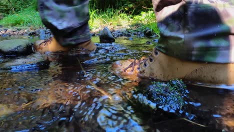 low angle waterproof boots splash and walk through river creek