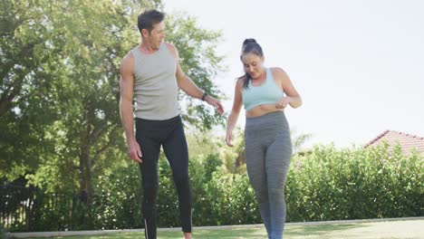 feliz pareja caucásica haciendo yoga y estirándose en un jardín soleado, cámara lenta