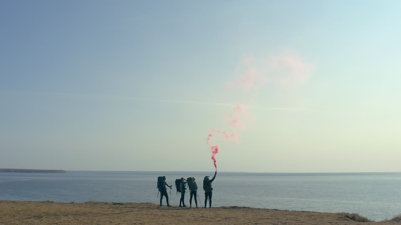 바다 근처의 모래 바위 꼭대기에 서 있는 불 지이를 가진 관광객들