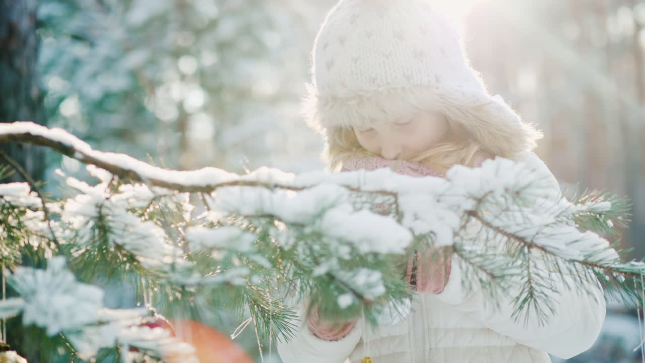 따뜻한 니트 모자를 쓴 어린 소녀는 크리스마스를 준비하고 새해 나무를 colorf로 장식합니다