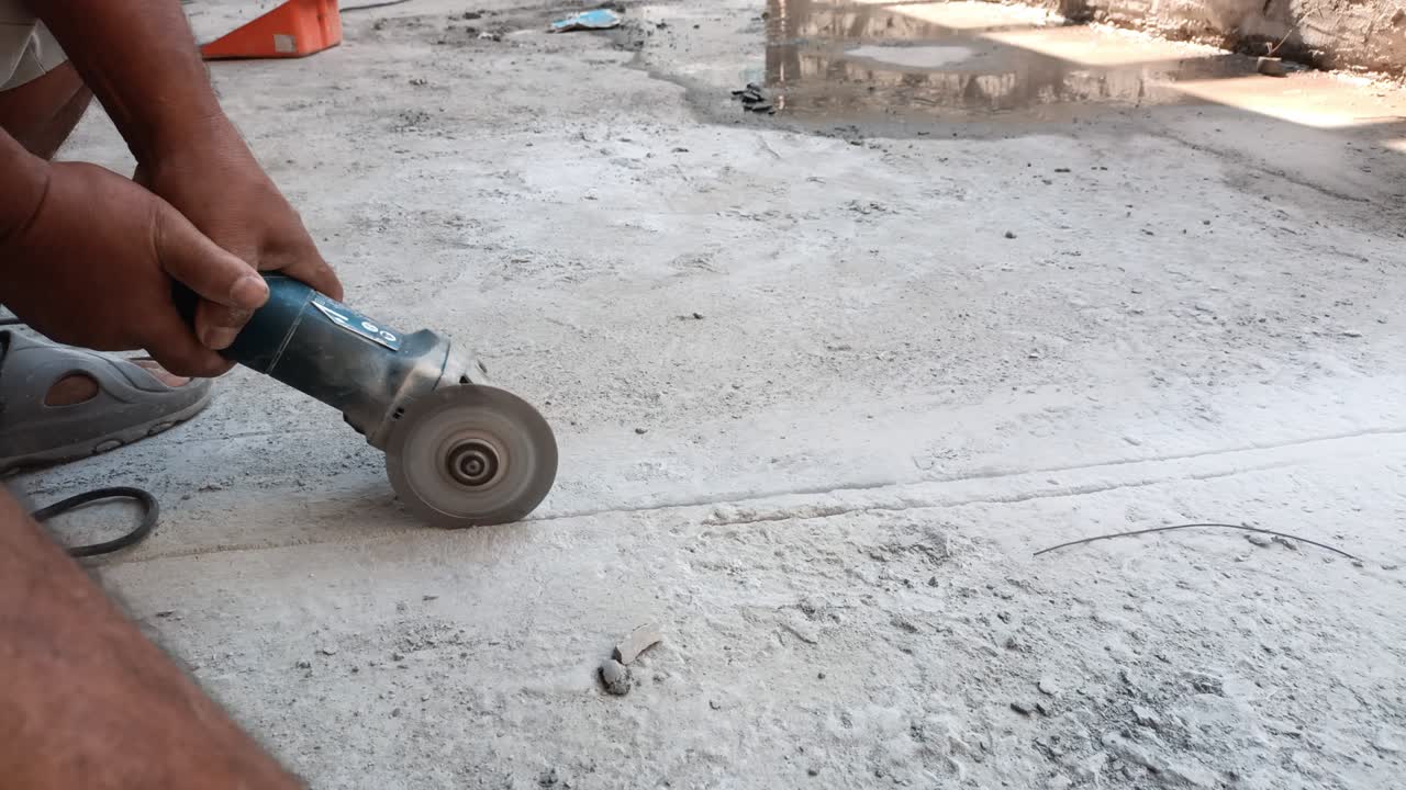 전기 배선을 놓기 위해 전기 로 콘크리트 바닥을 자르는 밀러를 사용하여 작업자의 손을 가까이