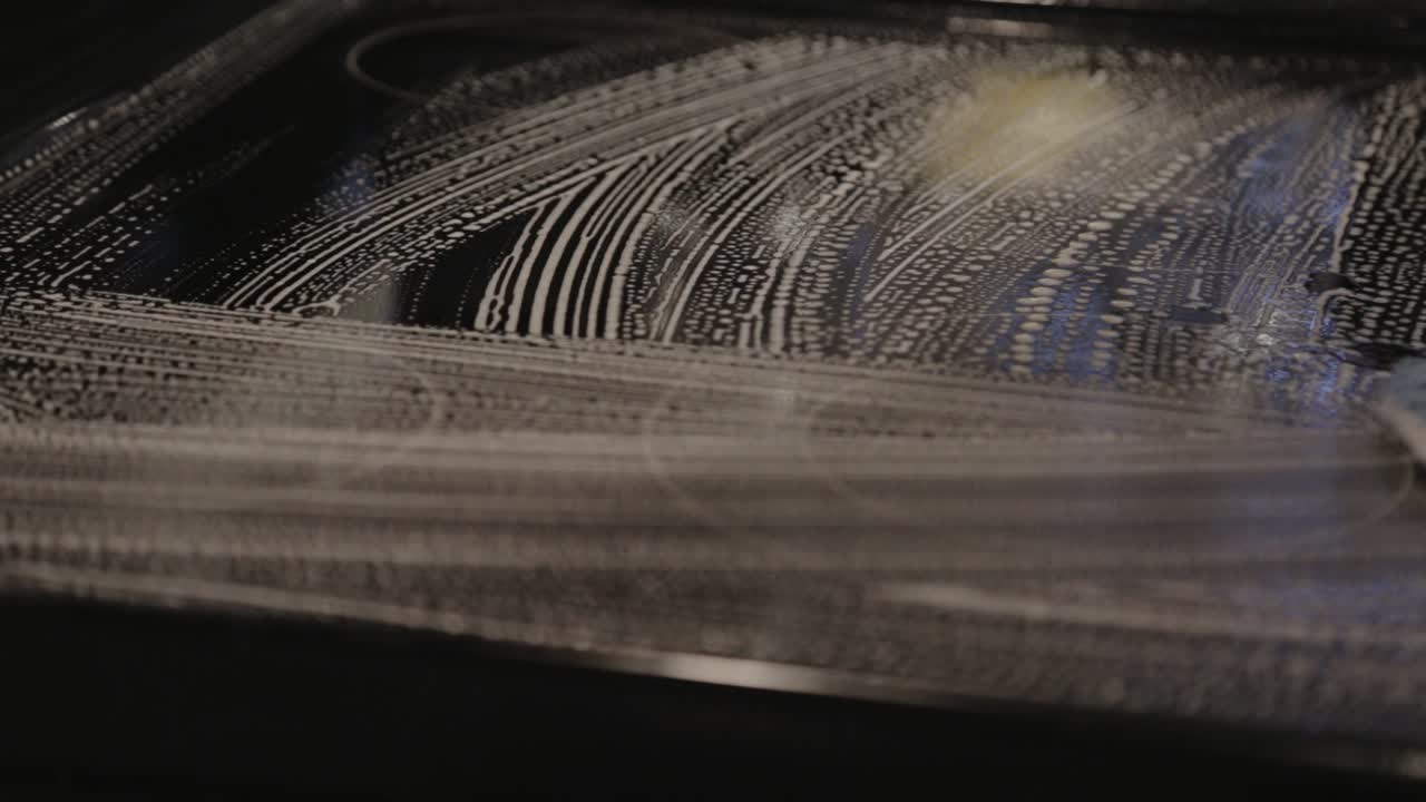 부엌에 있는 유리 버너에 조심스럽게 거품을 낸 비누 - 클로즈업 샷