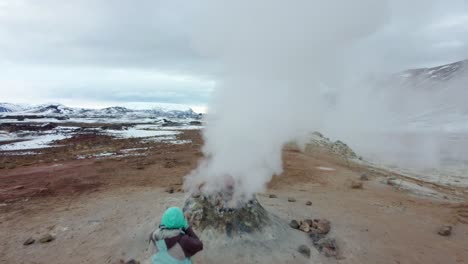 woman watching geothermal field with fumaroles and geysers