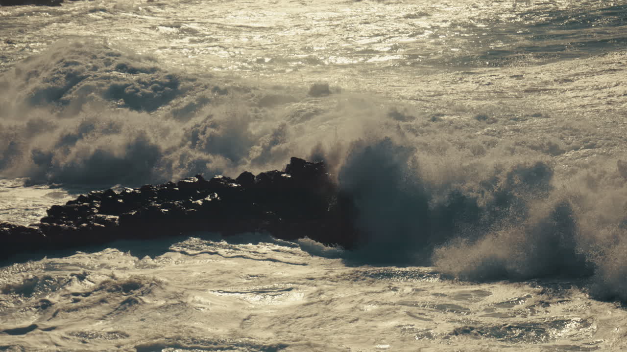 강한 파도가 바위 위에 부히고