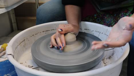 young woman artist making clay bowl on pottery wheel