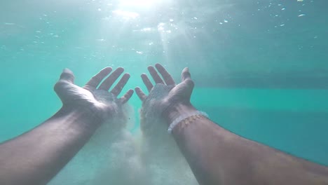 pov sand flowing from hands underwater. clear water in french polynesia moorea