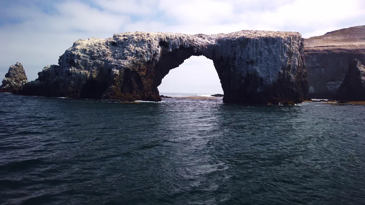 Gimbal close-up and tilting up shot from a moving boat of the famous Arch Rock off East Anacapa Island in Channel Islands National Park, California