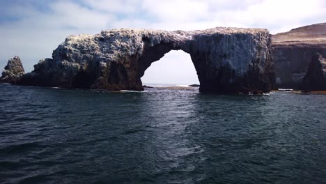 Gimbal-close-up-and-tilting-up-shot-from-a-moving-boat-of-the-famous-Arch-Rock-off-East-Anacapa-Island-in-Channel-Islands-National-Park,-California